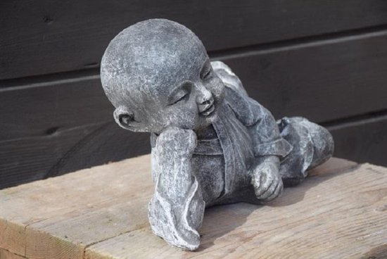 Figurine grise en béton d'un jeune moine couché sur le côté, les yeux fermés et une main sous sa joue.