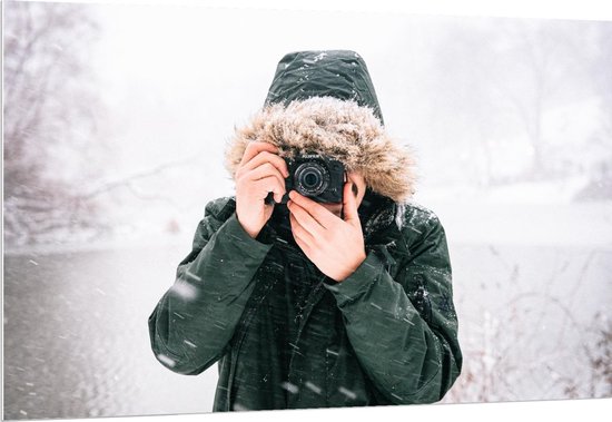 Forex - Man in de Sneeuw met een Donkere Jas met een Bontkraag en een Camera - 150x100cm Foto op Forex