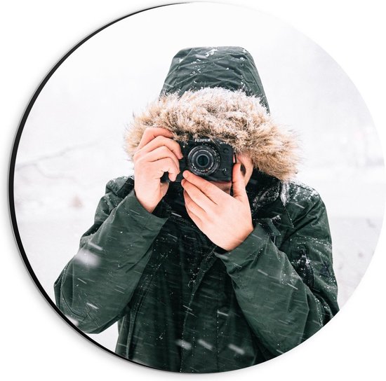 Dibond Wandcirkel - Man in de Sneeuw met een Donkere Jas met een Bontkraag en een Camera - 20x20cm Foto op Aluminium Wandcirkel (met ophangsysteem)