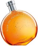 Elixir des Merveilles Eau de Parfum. Rond parfumflesje met zilverkleurige dop, gevuld met sprankelende oranje-gele vloeistof.