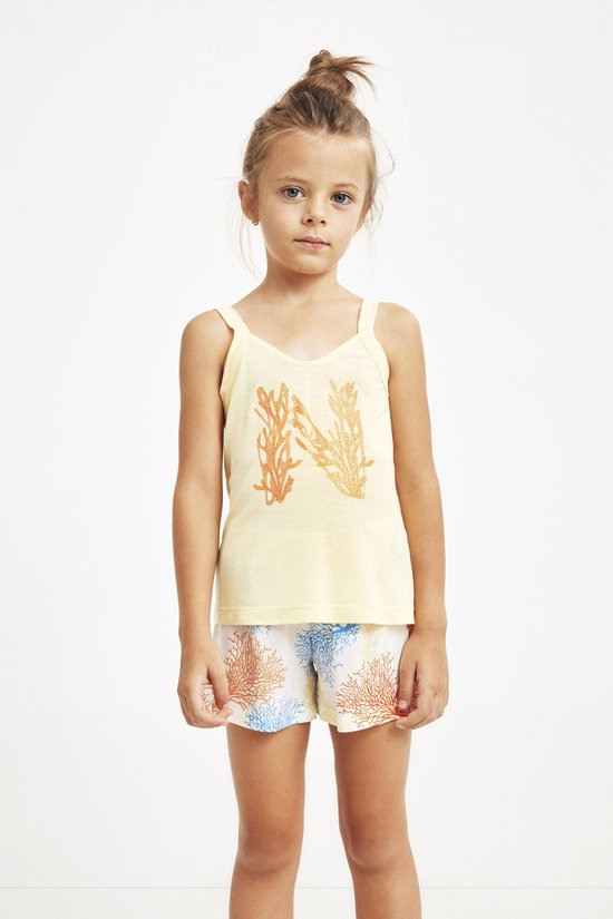 Une fille portant un débardeur jaune pâle avec un imprimé corail et un short à motifs coraux.