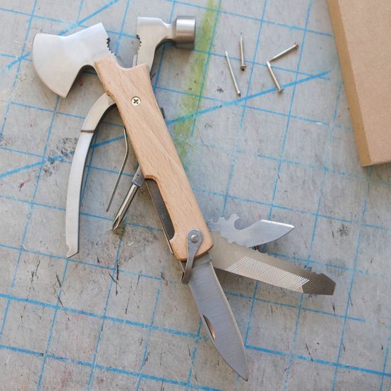 Uitgevouwen multitool met houten handvat, bijl, hamer, mes en tang. Naast de tool liggen spijkers.