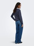 Zijaanzicht van een model in donkerblauw katoenen sweatshirt met "PARIS" in reliëf en een losse jeans.
