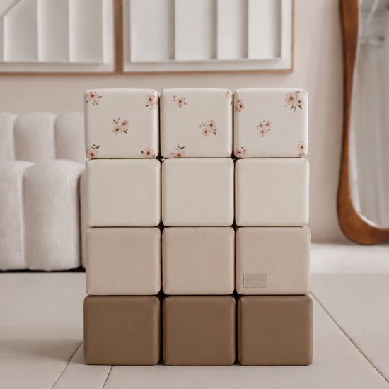 Twaalf zachte foam stapelblokken in crème, beige en bruine tinten. De bovenste rij blokken heeft een subtiel bloemenpatroon in roze en beige.