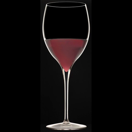 Een glas gevuld met rode wijn, staand op een zwarte achtergrond.