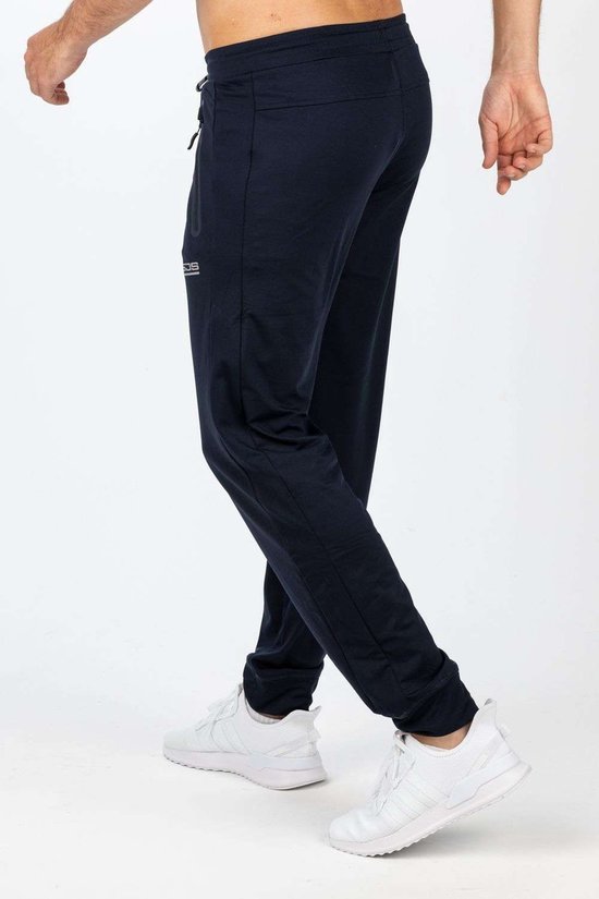 Donkerblauwe sportbroek met trekkoord en logo op de linkerpijp. Gedragen door een model met witte sneakers.