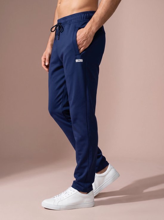 Marineblauwe joggingbroek met trekkoord en logo op linkerbeen, gedragen door een man met witte sneakers.