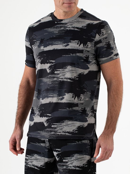 Man in sportshirt met camouflageprint in grijs en zwart, met logo op de borst.