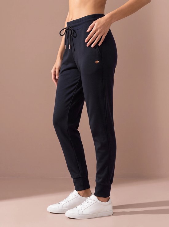 Donkerblauwe sportbroek met trekkoord, rosé gouden veteroogjes, een zak en een logoplaatje, gedragen door een model.