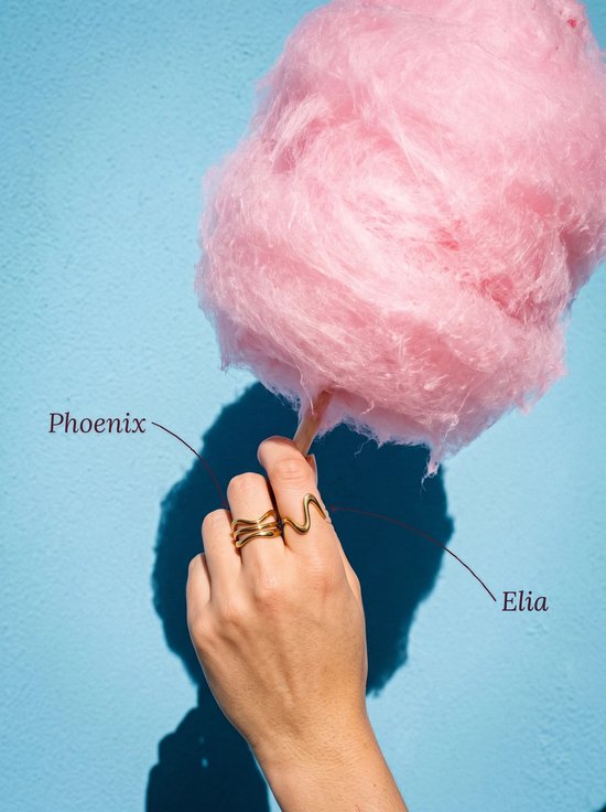Hand met een roze suikerspin die twee goudkleurige golvende ringen draagt, gelabeld als Phoenix en Elia.