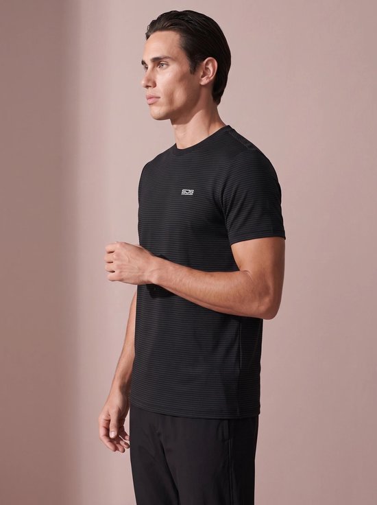Zijaanzicht van een man in een zwart, fijn gestreept sportshirt met SJS-logo, gecombineerd met zwarte sportbroek.