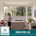 Een vrouw in een lichte keuken met een raamfolie met textielstructuur aangebracht op het keukenraam.