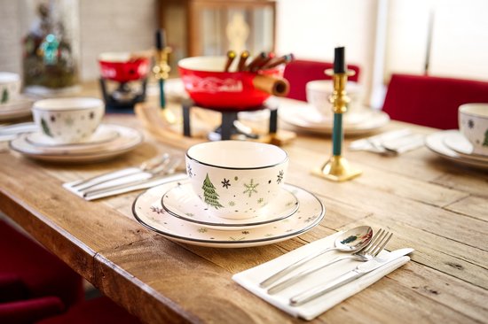 Gedekte tafel met kerstservies: borden en kommen met kerstboom- en sneeuwvlokmotief.