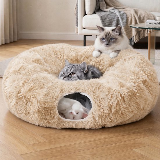 Twee katten en een kitten in een ronde, beige, pluizige kattentunnel met een ronde opening.