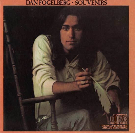 Dan Fogelberg zit in een stoel met een veer in zijn hand. De tekst 'Dan Fogelberg Souvenirs' staat bovenaan.