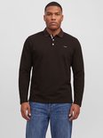 Model draagt een bruine polo met lange mouwen en jeans, met Jack & Jones merkdetail op de borst.