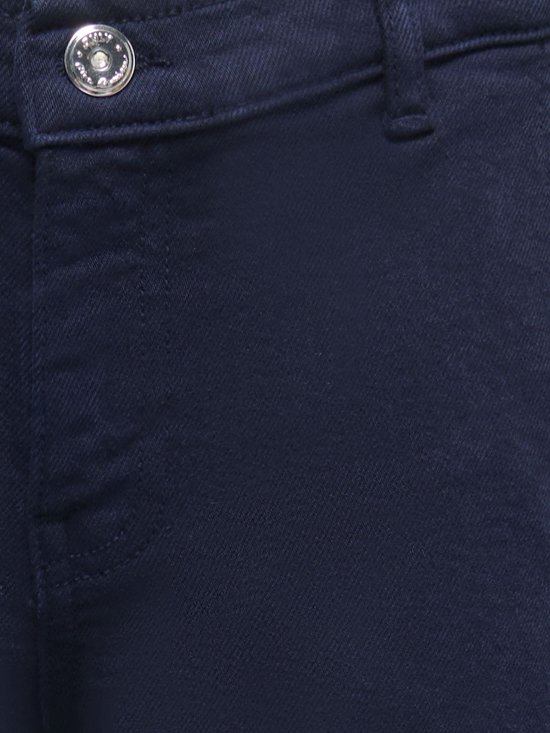 Close-up van de tailleband van een donkerblauwe spijkerbroek met knoopsluiting en merklogo.