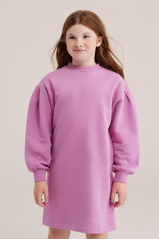 Kind in roze oversized sweatshirtjurk met pofmouwen en geribbelde boorden.
