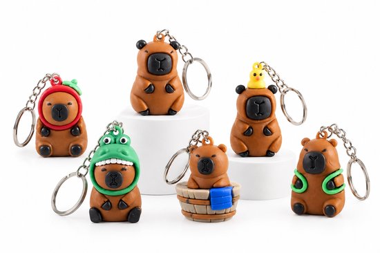 Six porte-clés capybara marron avec divers accessoires comme des bonnets, un petit canard et une baignoire.