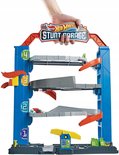 Hand houdt een blauwe Hot Wheels Stunt Garage met vier verdiepingen vast, inclusief hellingen en parkeernummers.