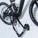 Groene elektrische mountainbike bevestigd met een zwarte ABUS ketting aan een muuranker.