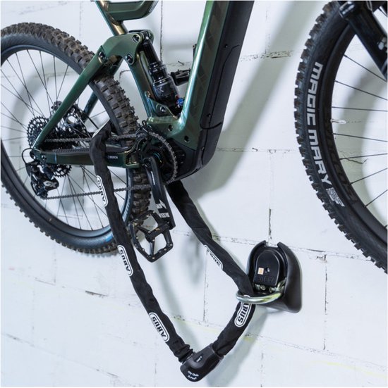 Groene elektrische mountainbike bevestigd met een zwarte ABUS ketting aan een muuranker.