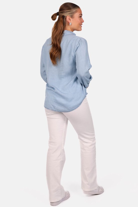 Model van achteren gezien, draagt een lichtblauwe Tencel blouse en een witte broek.