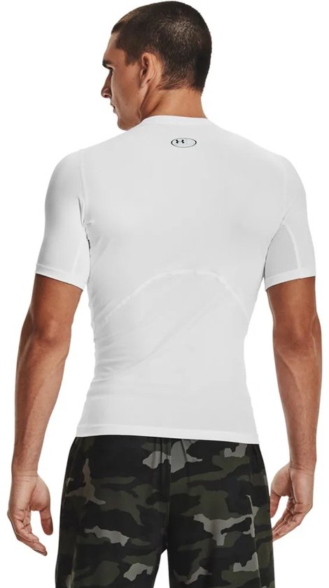 Rug van man met kort wit Under Armour Heatgear shirt en camouflage shorts.