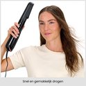 Femme tenant la brosse soufflante noire pour un séchage rapide et facile.