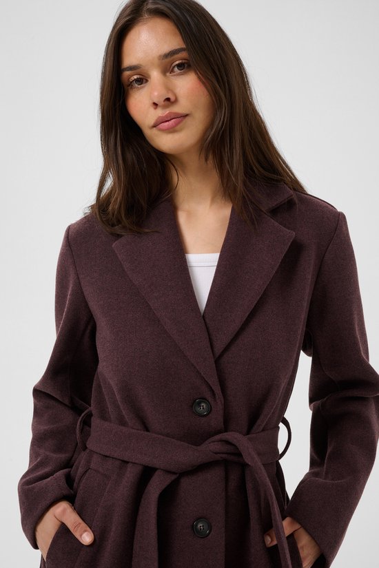 Model draagt een bordeauxrode wollen jas met reverskraag, knopen en een ceintuur in de taille.