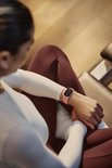 Close-up van vrouw in sportkleding die naar de Fitbit Edge om haar pols kijkt.