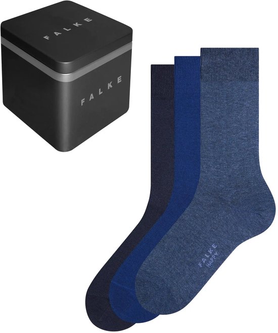 Drie paar blauwe Falke Happy sokken in gradaties van donker naar licht, naast een zwarte metalen Falke geschenkdoos.