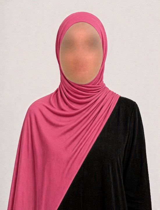 Model draagt een roze jersey hijab, gedrapeerd over de schouder, gecombineerd met een zwarte top.