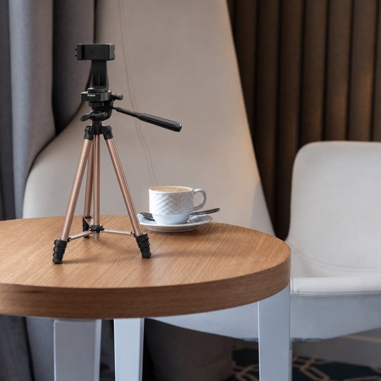 Stijlvol mat bronzen YSONIC statief op houten tafel naast een kopje koffie.