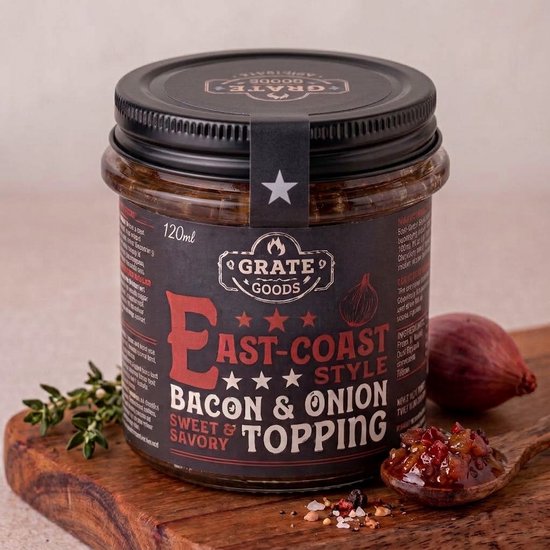 Pot Grate Goods East-Coast Style bacon- en uientopping van 120 ml met een sjalotje en een lepel topping op een plank.