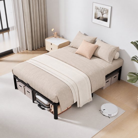 Zwart metalen bedframe van 160x200 cm met linnen beddengoed, decoratieve kussens en opbergboxen onder het bed.