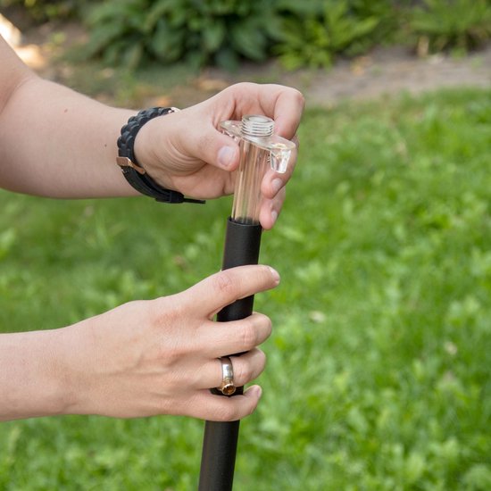 Handen plaatsen een transparant kunststof verbindingsstuk op een zwarte metalen paal.