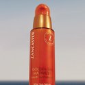 Lancaster Golden Tan Maximizer aftersun serum in een oranje pompflacon tegen een blauwe lucht.