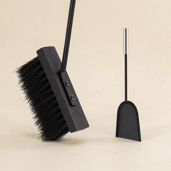Bezem met zwarte haren en een metalen schep, beide met zilverkleurige handvatten.