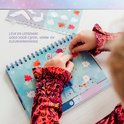 Enfant en chemisier coloré collant des autocollants de feuilles d'automne par numéro dans un cahier La Reine des Neiges.