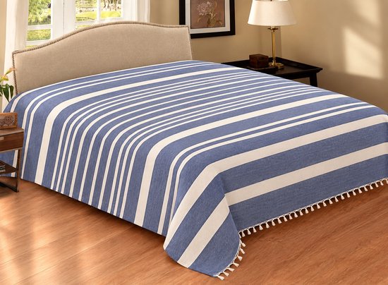 Bed opgemaakt met een blauw-witte gestreepte sprei met franjes aan de rand.