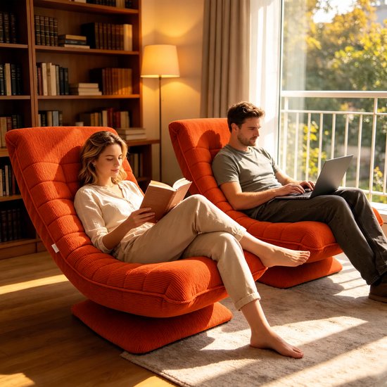 Twee oranje corduroy draaifauteuils in een woonkamer; een vrouw leest een boek en een man werkt op een laptop.