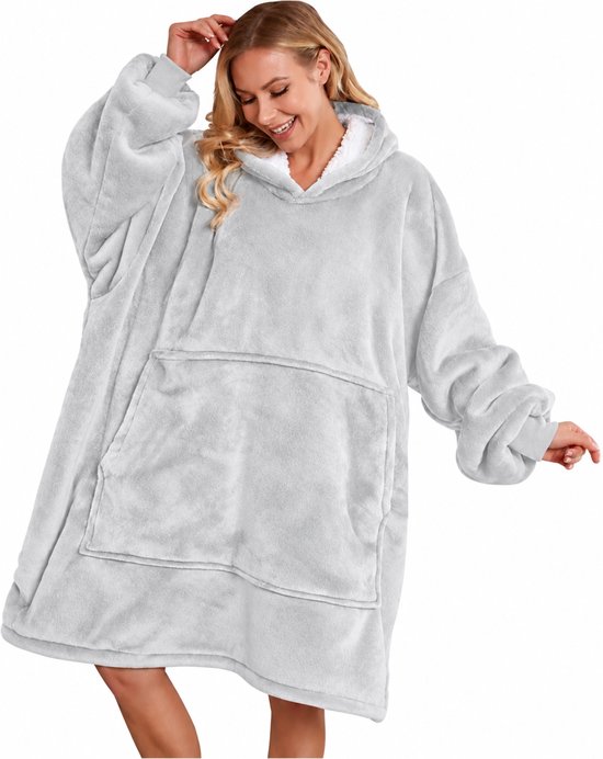 Vrouw draagt een oversized, lichtgrijze fleece hoodie-deken met witte voering, capuchon en grote voorzak.