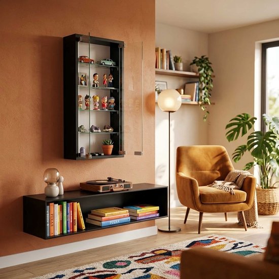 Zwarte vitrinekast aan een muur met sierobjecten, naast een fauteuil en een kastje.