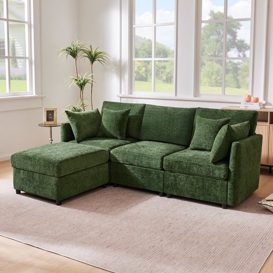 Groene modulaire hoekbank met hocker in een woonkamer met grote ramen.