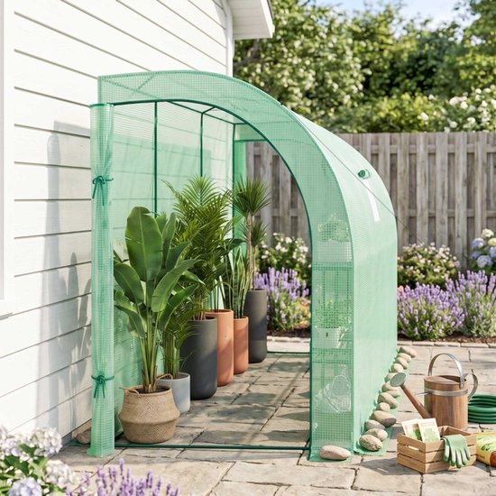 Groene kweektent op een terras met planten, gieter en tuinaccessoires.