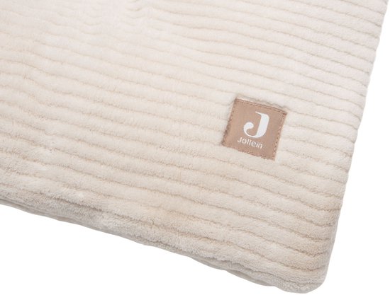 Close-up van een lichtbeige boxkleed met ribbelpatroon, met een label met het Jollein logo.
