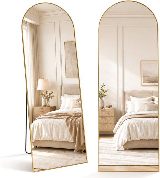 Een grote staande spiegel met gouden rand, reflecteert een slaapkamer met een opgemaakt bed.