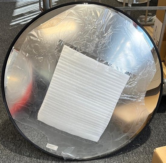 Convexe veiligheidsspiegel met een zwarte rand, beschermd met plastic folie en schuim.