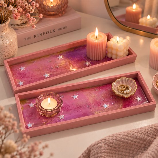 Twee roze rechthoekige houten dienbladen met een glinsterende roze epoxy bodem met sterren, decoratief opgesteld.